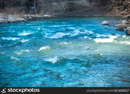 Blue river water with waves streaming near banks