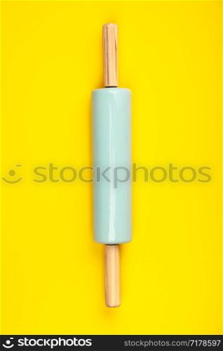 Blue rolling pin on yellow background, flat lay. Baking or cooking concept. Blue rolling pin on yellow background, flat lay