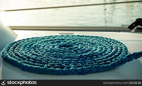 Blue rope coiled on dock. Part of sailboat yacht detail.