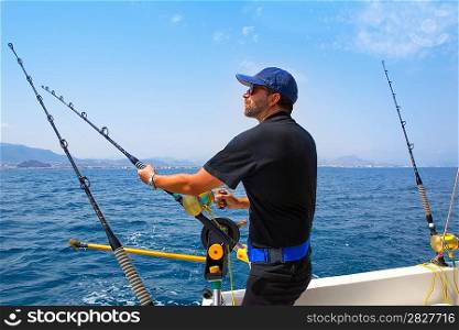 blue sea fisherman in trolling boat in action with downrigger and rod