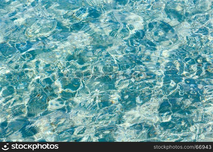 Blue sea flowing water surface with waves and sun glitters. Abstract background pattern.