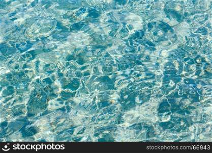 Blue sea flowing water surface with waves and sun glitters. Abstract background pattern.