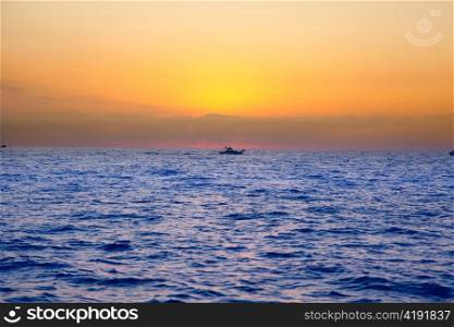 blue sea sunrise with sun in horizon with fishing boat sailing