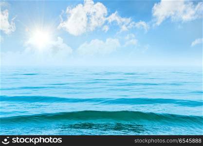 Blue sea water with waves. Blue sea water with waves, sun and white clouds on the sky. Calm tropical landscape