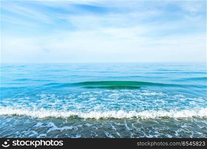 Blue sea water with waves, foam and white clouds on the sky. Calm tropical landscape. Blue sea water with waves