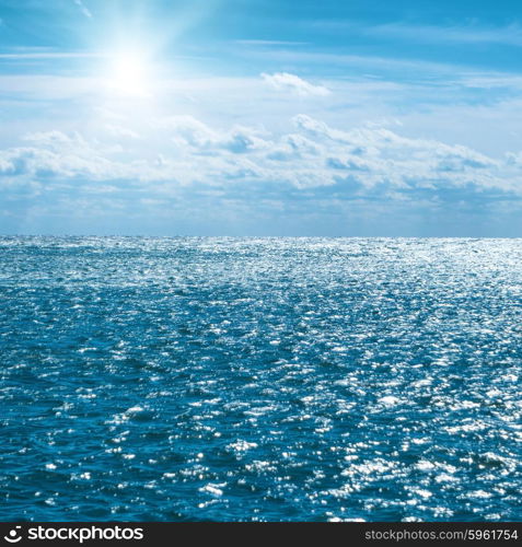 Blue sea with sky, sun and clouds. Water natural background