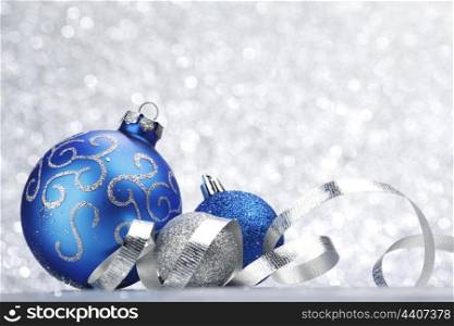 Blue shiny christmas ball on silver glitter background