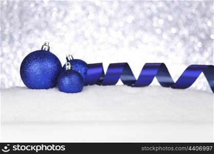 Blue shiny Christmas balls and ribbon on snow