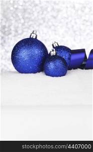 Blue shiny Christmas balls and ribbon on snow