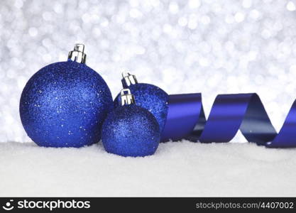 Blue shiny Christmas balls and ribbon on snow