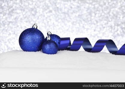 Blue shiny Christmas balls and ribbon on snow