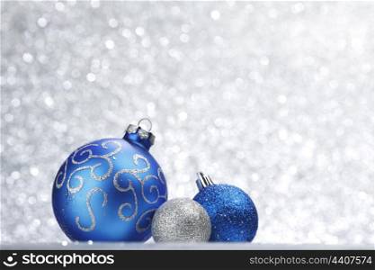 Blue shiny christmas balls on silver glitter background