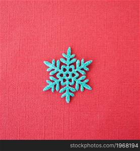 blue shiny snowflake on red paper background.
