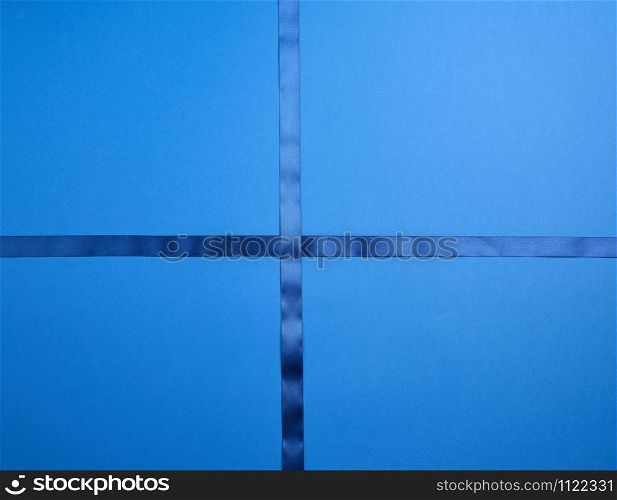 blue silk ribbon crossed on a dark blue background, imitation of tying a gift, top view