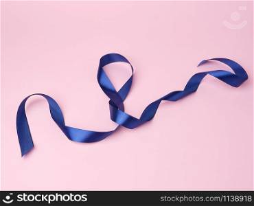 blue silk thin ribbon twisted on a pink background, trendy classic color, close up