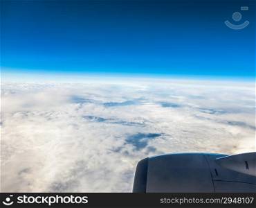 Blue sky and engine. View from window of airplane flying in clouds. Skyscape cloudscape. Bird&#39;s eye.