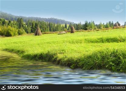 Blue sky and green grass near the water in Carpathian mountains