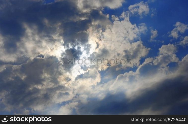 Blue sky and heavy clouds and the sun behind
