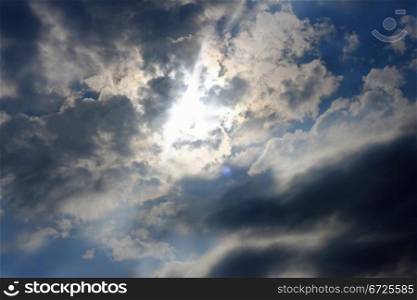 Blue sky and heavy clouds and the sun behind
