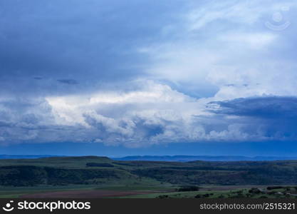 Blue sky and white cumulus clouds over green landscape after sunset Drakensberg South Africa