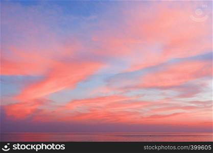Blue sky at sunset with clouds of color living coral around the sea. Natural beautiful background. View of the blue-pink sky with clouds at sunset in the background of the sea. Beautiful natural layout