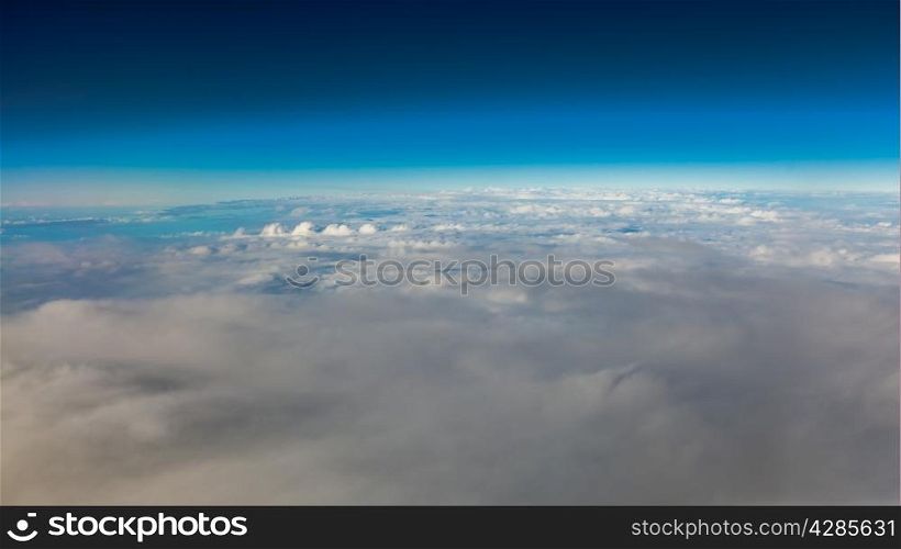 Blue sky. View from window of airplane flying in clouds. Skyscape cloudscape. Bird&#39;s eye.