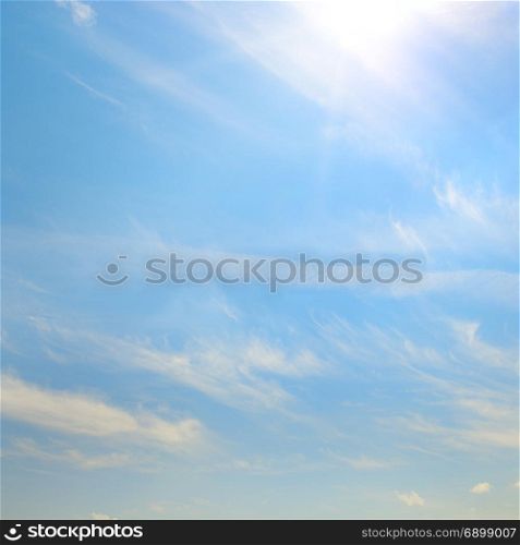 Blue sky with bright sun. Heavenly background with clouds.