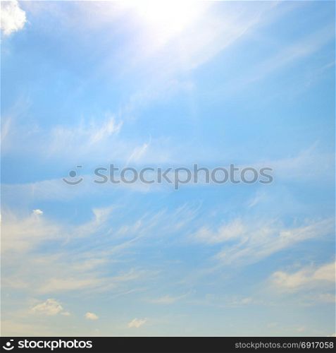 Blue sky with bright sun. Heavenly background with white clouds.