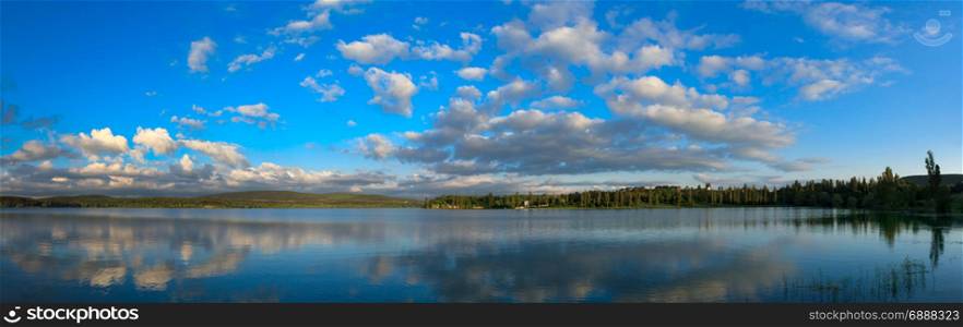 Blue sky with sun over water.. natural reflections on a lake and beautiful clouds.
