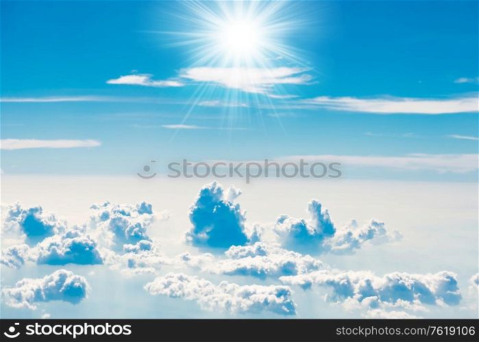 Blue sky with white clouds and shining sun rays, above aerial view from a plane, nature blue sky background
