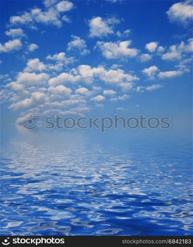 Blue sky with white clouds reflected in the water surface with small waves