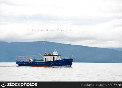 blue small motor craft goes at foggy Baikal