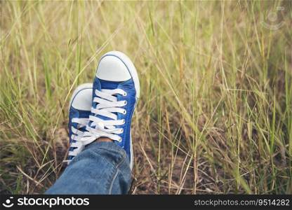 Blue sneaker, Pretty woman wear jeans and a blue sneaker on a green meadow.