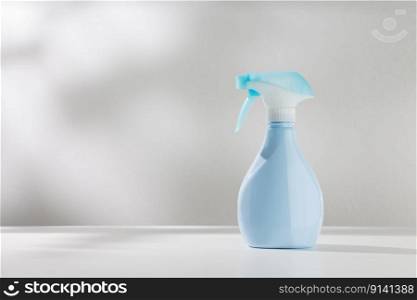 Blue spray bottle on a white wooden table.