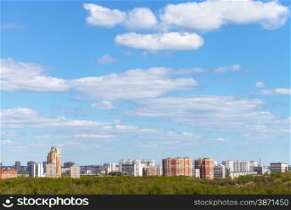 blue spring sky with white clouds over city and green woods in sunny day