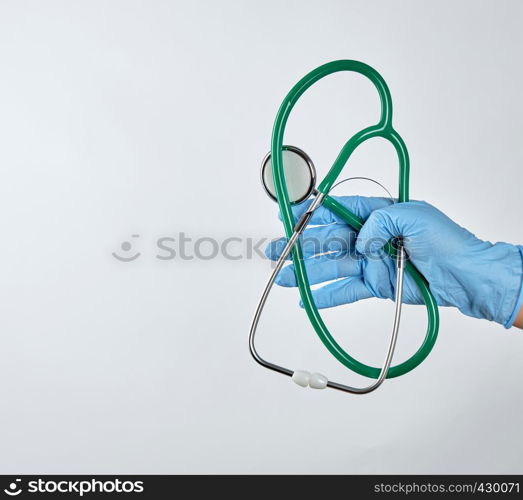 blue sterile gloved hand holding a green medical stethoscope on white background, copy space