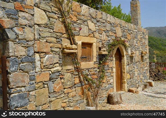 Blue stone Cretan typical house with a vineyard and a window and a wooden door