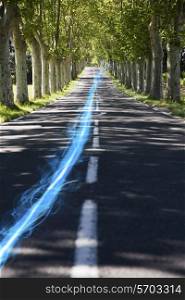 Blue streak of light on country road along trees