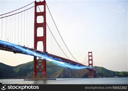 Blue streak of light passing by Golden Gate Bridge against clear sky