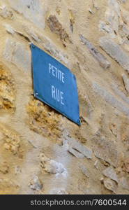Blue street name sign in French town: `Small Street`.