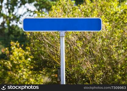 Blue street sign with no text in green nature in the summer