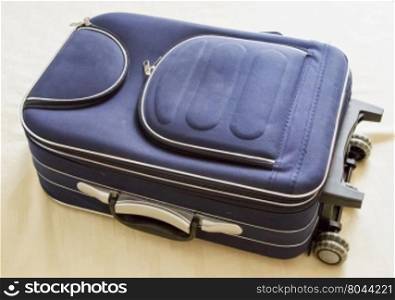 Blue suitcase over bed cover, horizontal image