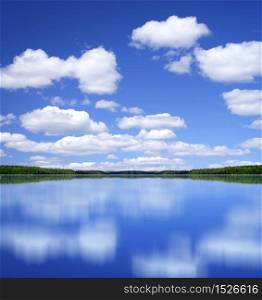 Blue summer sky with white clouds mirror perfect reflection from lake surface