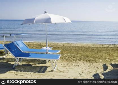Blue sunbeds and umbrellas on the beach.