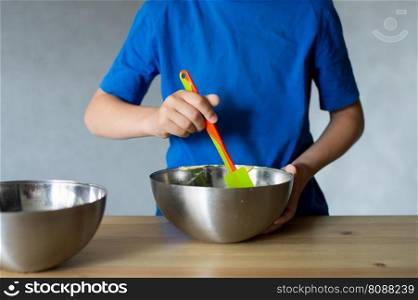 blue t-shirt, cooking, two bowls, metal bowls, pizza dough, mix ingredients, kitchen work, wooden table, baking, baby in the kitchen. A child prepares dough in metal bowls. Without a face