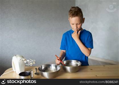 blue t-shirt, cooking, two bowls, metal bowls, pizza dough, mix ingredients, kitchen work, wooden table, baking, baby in the kitchen, trying dough, finger in mouth, mixer, cooking, dessert, pastry chef, pawar, kitchen. A child prepares dough in metal bowls. Trying the dough