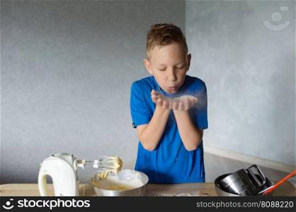 blue t-shirt, cooking, two bowls, metal bowls, pizza dough, mixing ingredients, kitchen work, wooden table, baking, child in the kitchen, mixer in a plate, children’s hands, cooking, dessert, pastry chef, pavar, kitchen. The child prepares the dough for baking by scattering flour. Hands in flour