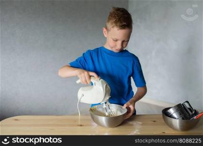 blue t-shirt, cooking, two bowls, metal bowls, pizza dough, mixing ingredients, kitchen work, wooden table, baking, child in the kitchen, mixer in a plate, children&rsquo;s hands, cooking, dessert, pastry chef, pavar, kitchen. A child prepares dough in metal bowls. Lower the mixer into the bowl