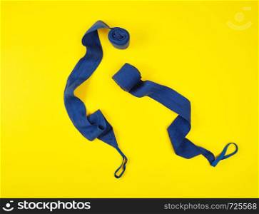 blue textile bandage for wrapping hands when playing sports on a yellow background, flat lay