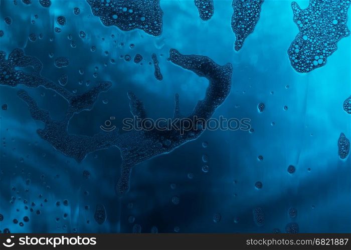 Blue texture with natural soap foam pattern on glass